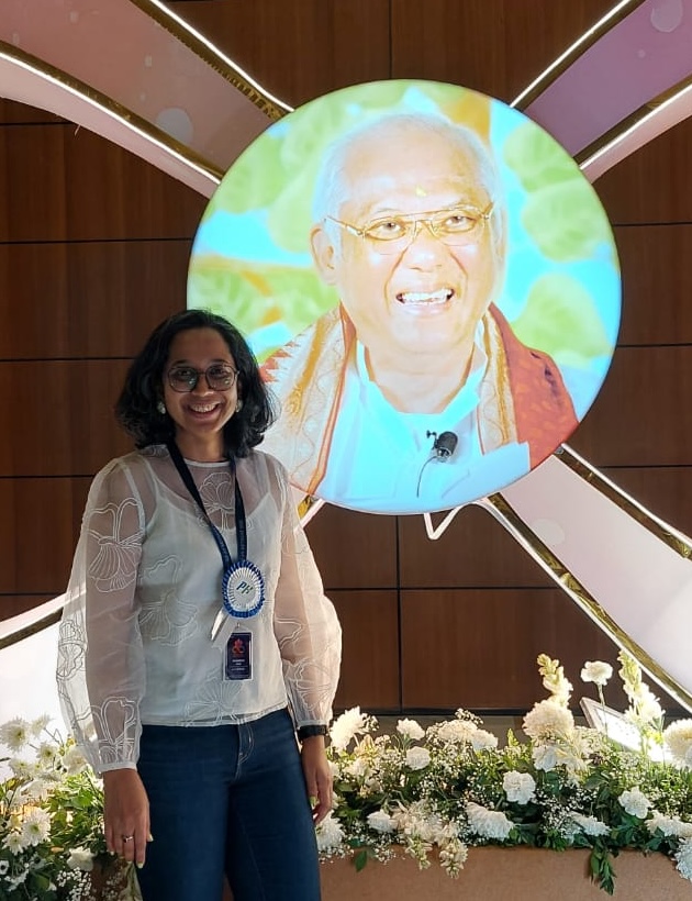 Khadeeja Khan, founder of Pranic Healing - Divine Lotus, standing in front of a large portrait of Grand Master Choa Kok Sui